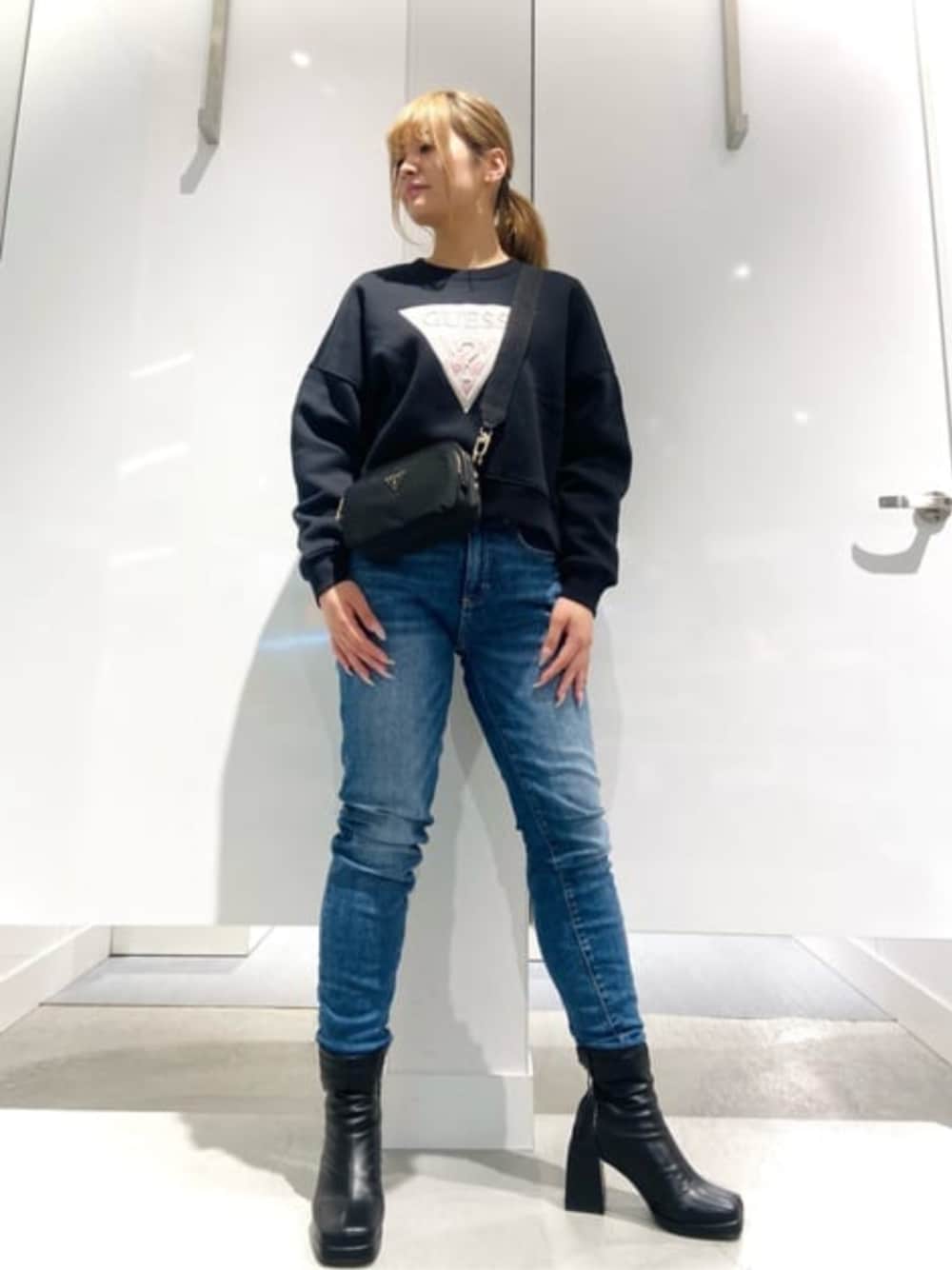 ブラック系のショルダーバッグ、ブルー系のデニムパンツ、ブラック系のスウェットを着用したレディースの春コーディネートの1枚目の写真