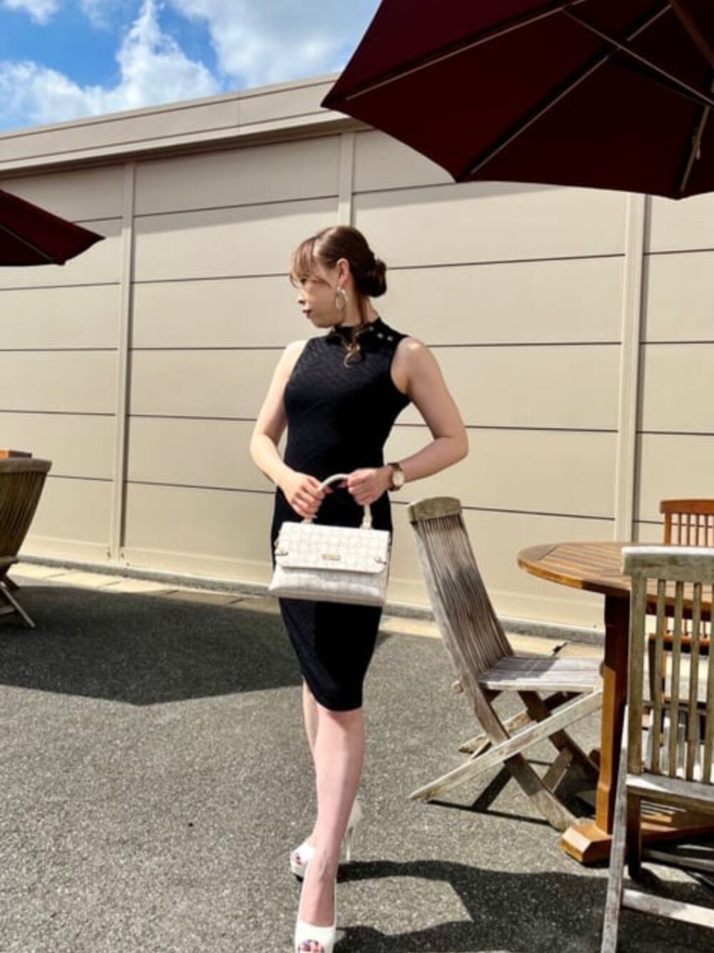 ホワイト系のハンドバッグ、ブラック系のワンピースを着用したレディースの夏コーディネートの1枚目の写真