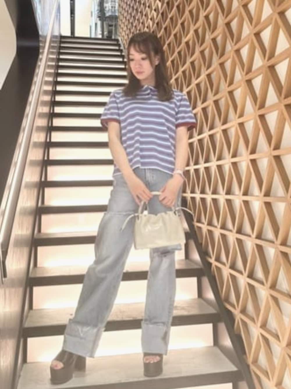 ブルー系のデニムパンツ、ブルー系のポロシャツ、ベージュ系のショルダーバッグを着用したレディースの夏コーディネートの1枚目の写真