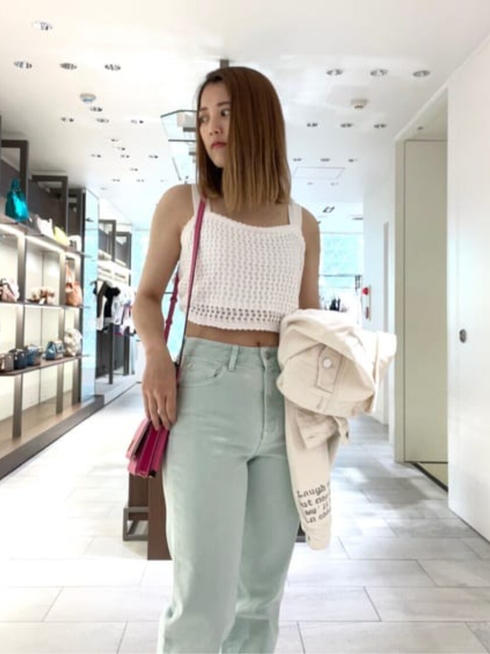 ピンク系のショルダーバッグ、ホワイト系のその他トップス、グリーン系のデニムパンツを着用したレディースの夏コーディネートの1枚目の写真