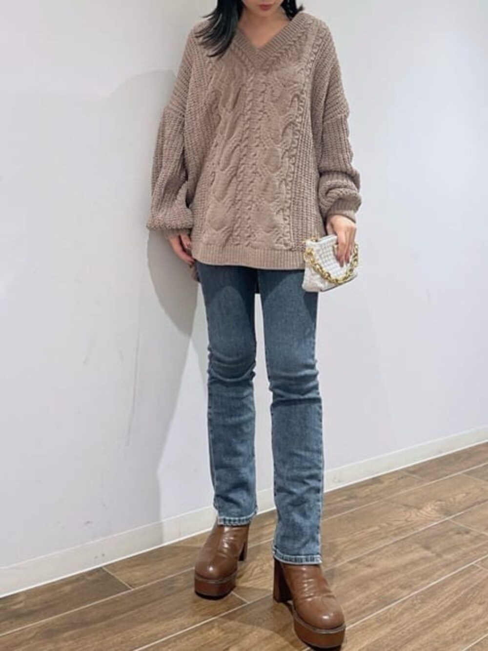 ホワイト系のショルダーバッグ、ブルー系のデニムパンツ、ベージュ系のニット/セーターを着用したレディースの冬コーディネートの1枚目の写真