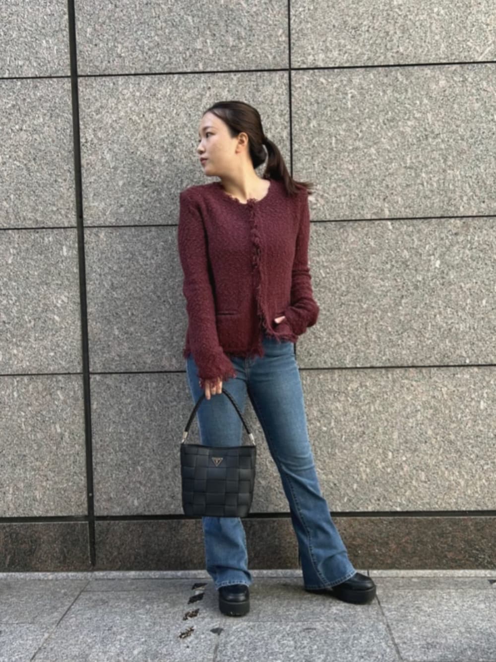 ブルー系のデニムパンツ、レッド系のノーカラージャケット、ブラック系のショルダーバッグを着用したレディースの秋コーディネートの1枚目の写真