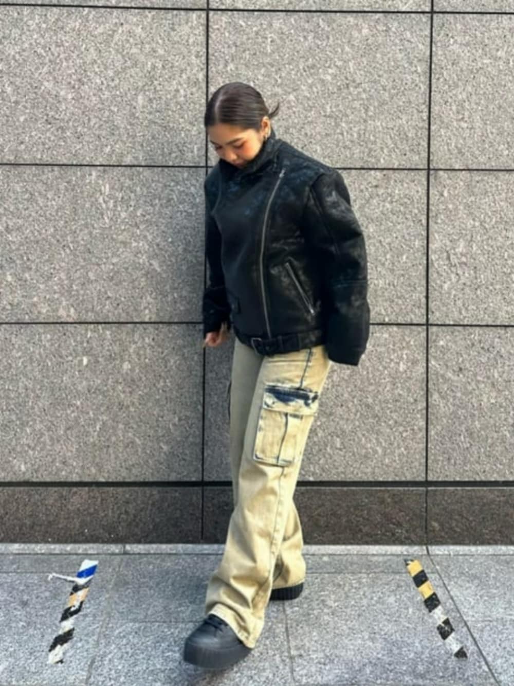 ブラック系のライダースジャケット、イエロー系のカーゴパンツを着用したレディースの秋コーディネートの1枚目の写真