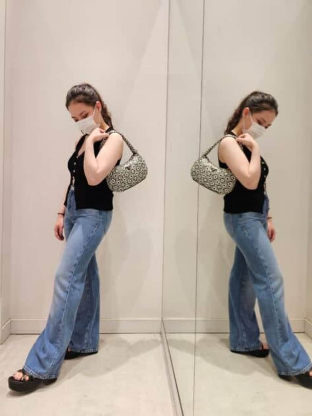 ブルー系のデニムパンツ、ブラック系のショルダーバッグ、ブラック系のタンクトップを着用したレディースの春コーディネートの1枚目の写真