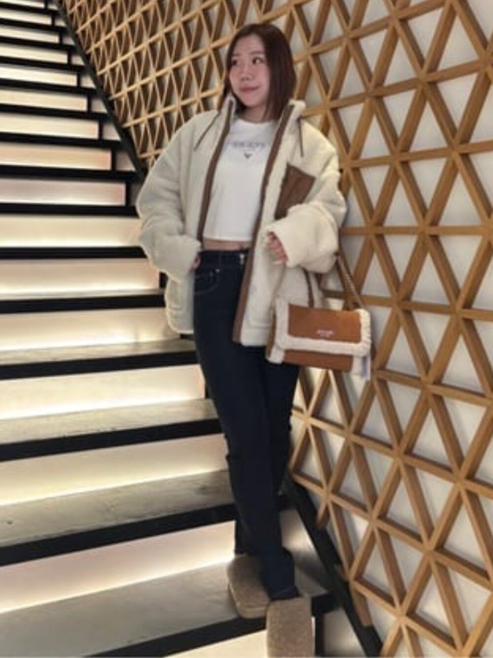 ブラウン系のショルダーバッグ、ブルー系のデニムパンツ、ホワイト系のTシャツ/カットソーを着用したレディースの冬コーディネートの1枚目の写真