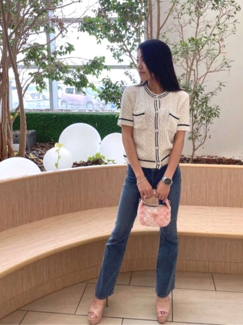 ブルー系のデニムパンツ、ピンク系のショルダーバッグ、ホワイト系のカーディガン/ボレロを着用したレディースの春コーディネートの1枚目の写真