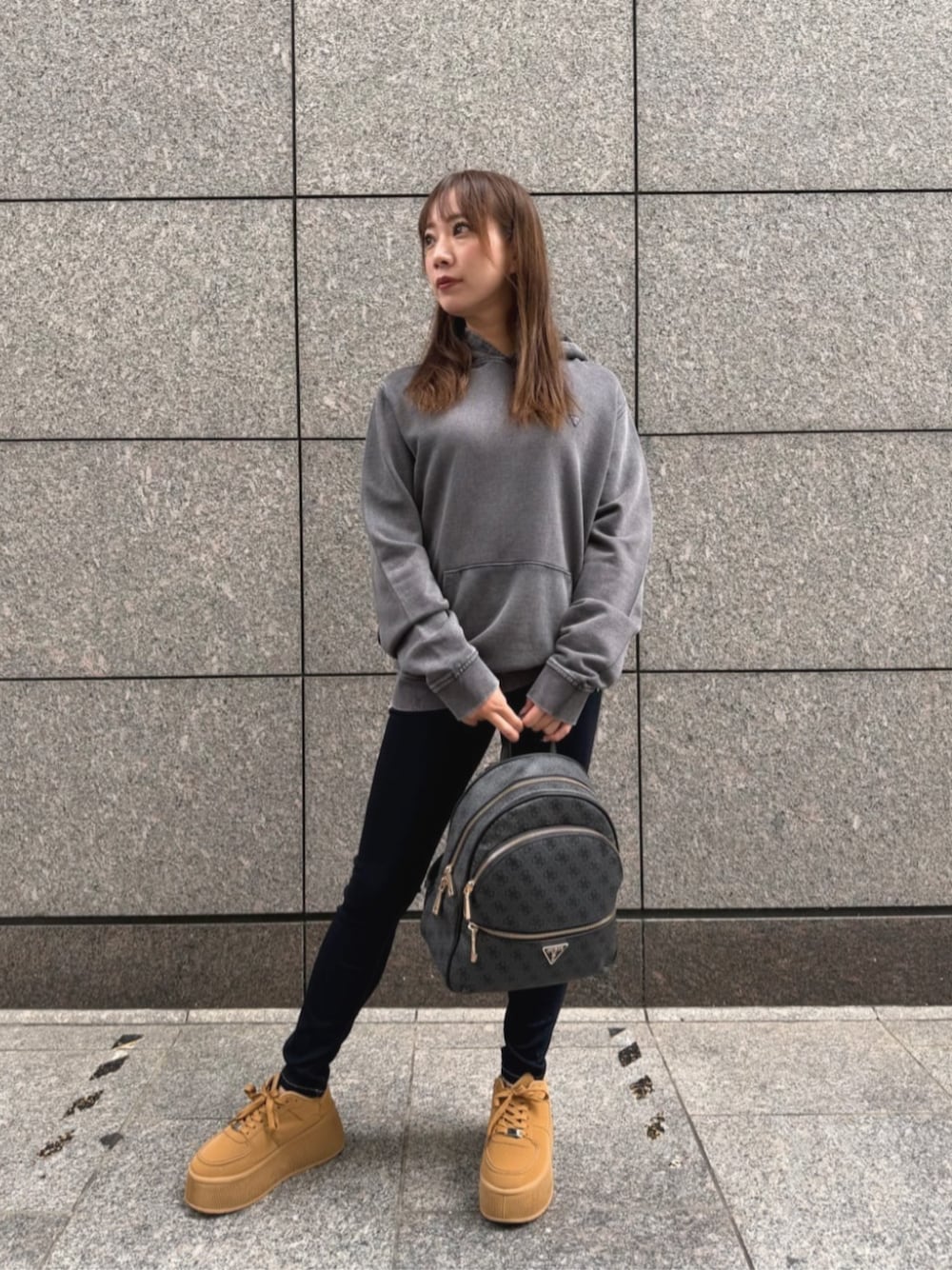 ブルー系のデニムパンツ、グレー系のバックパック/リュック、グレー系のパーカーを着用したレディースの秋コーディネートの1枚目の写真