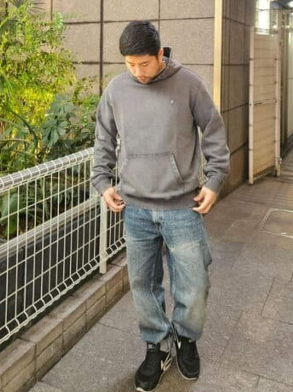 グレー系のパーカー、ブルー系のデニムパンツを着用したメンズの春コーディネートの1枚目の写真