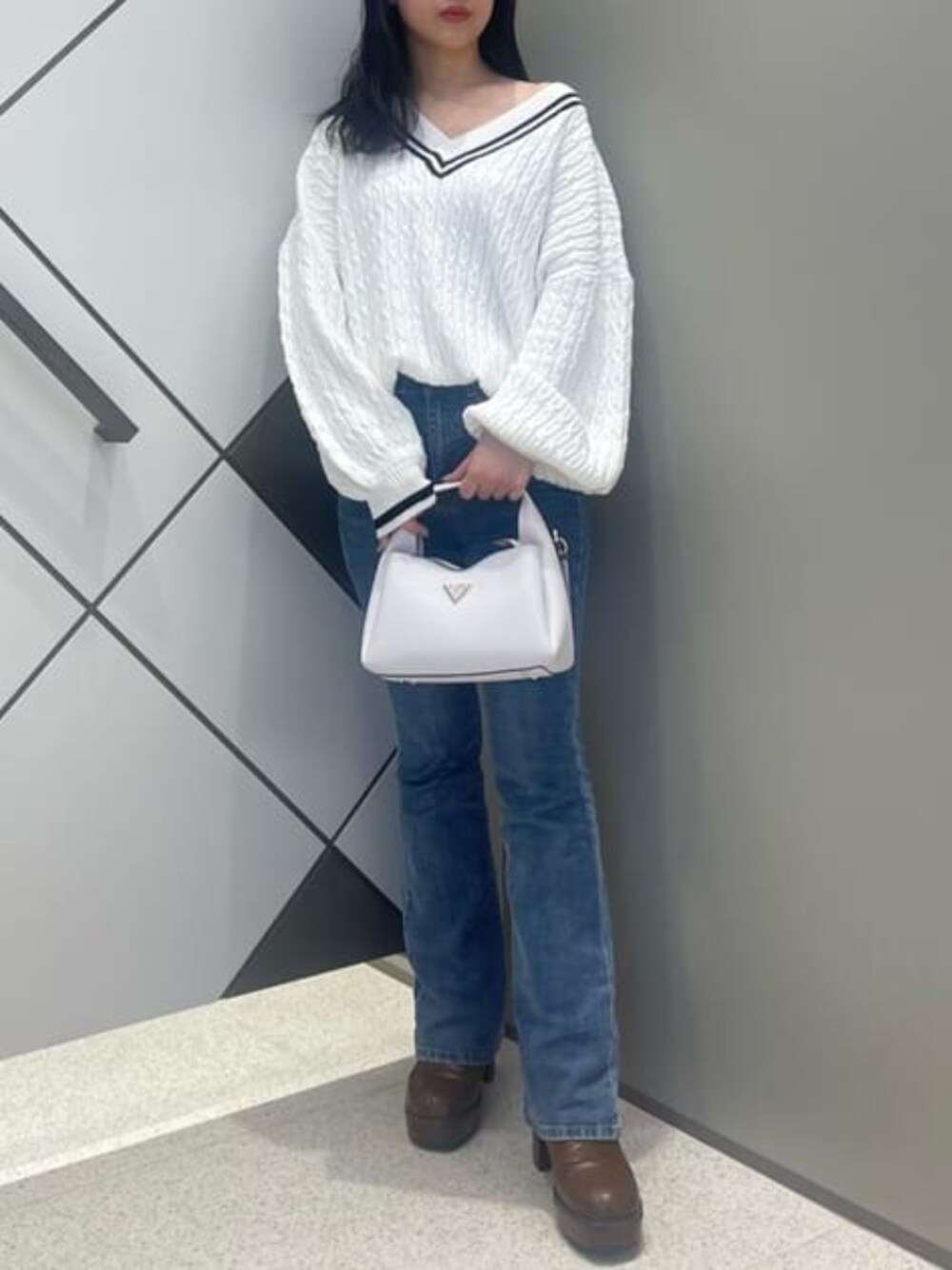 ブルー系のデニムパンツ、ホワイト系のショルダーバッグ、その他のニット/セーターを着用したレディースの春コーディネートの1枚目の写真