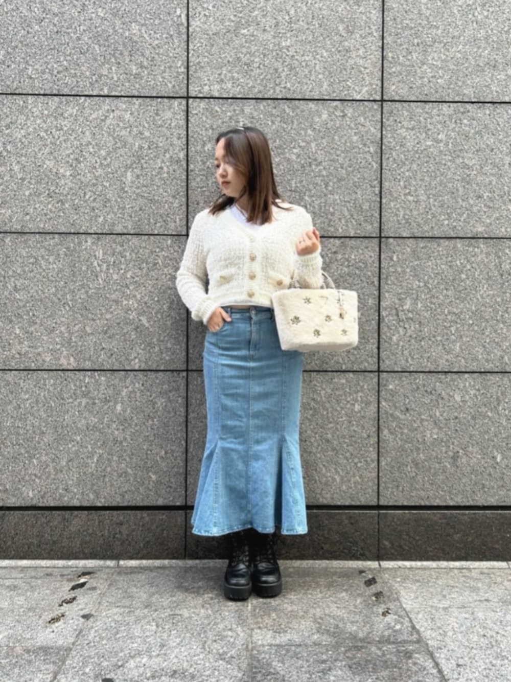 ブルー系のデニムスカート、ホワイト系のカーディガン/ボレロ、ホワイト系のショルダーバッグを着用したレディースの冬コーディネートの1枚目の写真