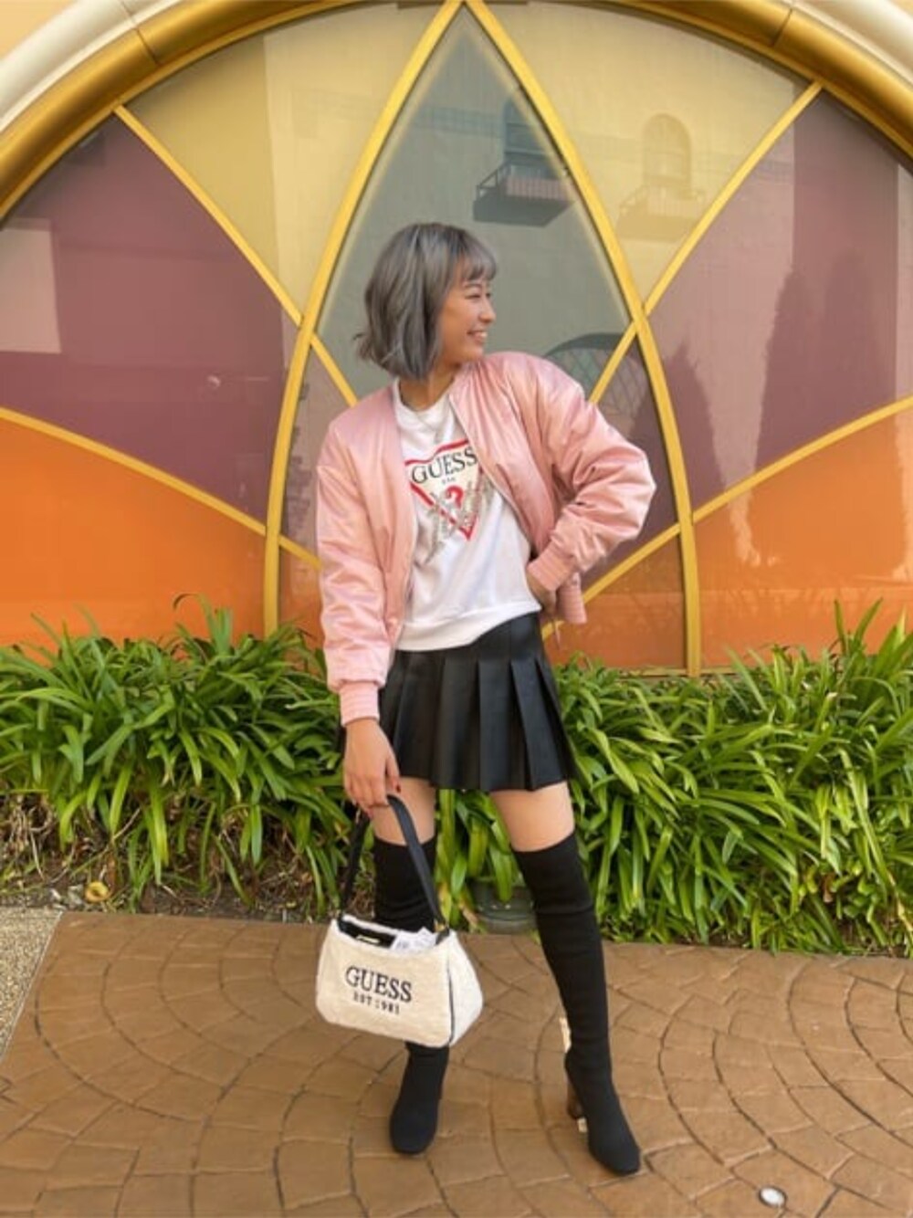 ピンク系のブルゾン、ベージュ系のショルダーバッグ、ブラック系のスカートを着用したレディースの冬コーディネートの1枚目の写真