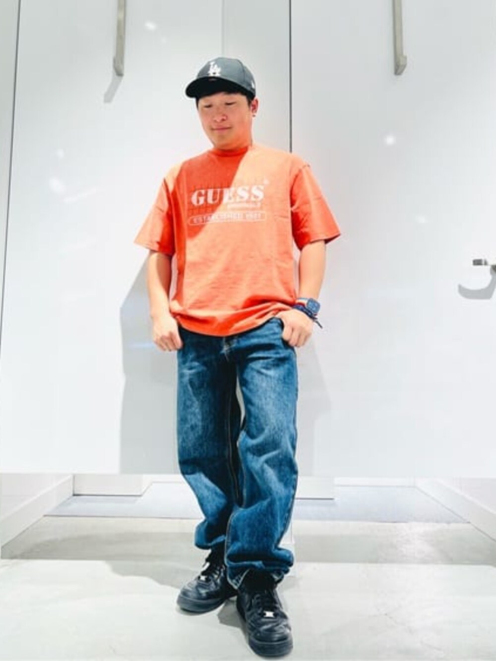オレンジ系のTシャツ/カットソー、ブルー系のデニムパンツを着用したメンズの春コーディネートの1枚目の写真