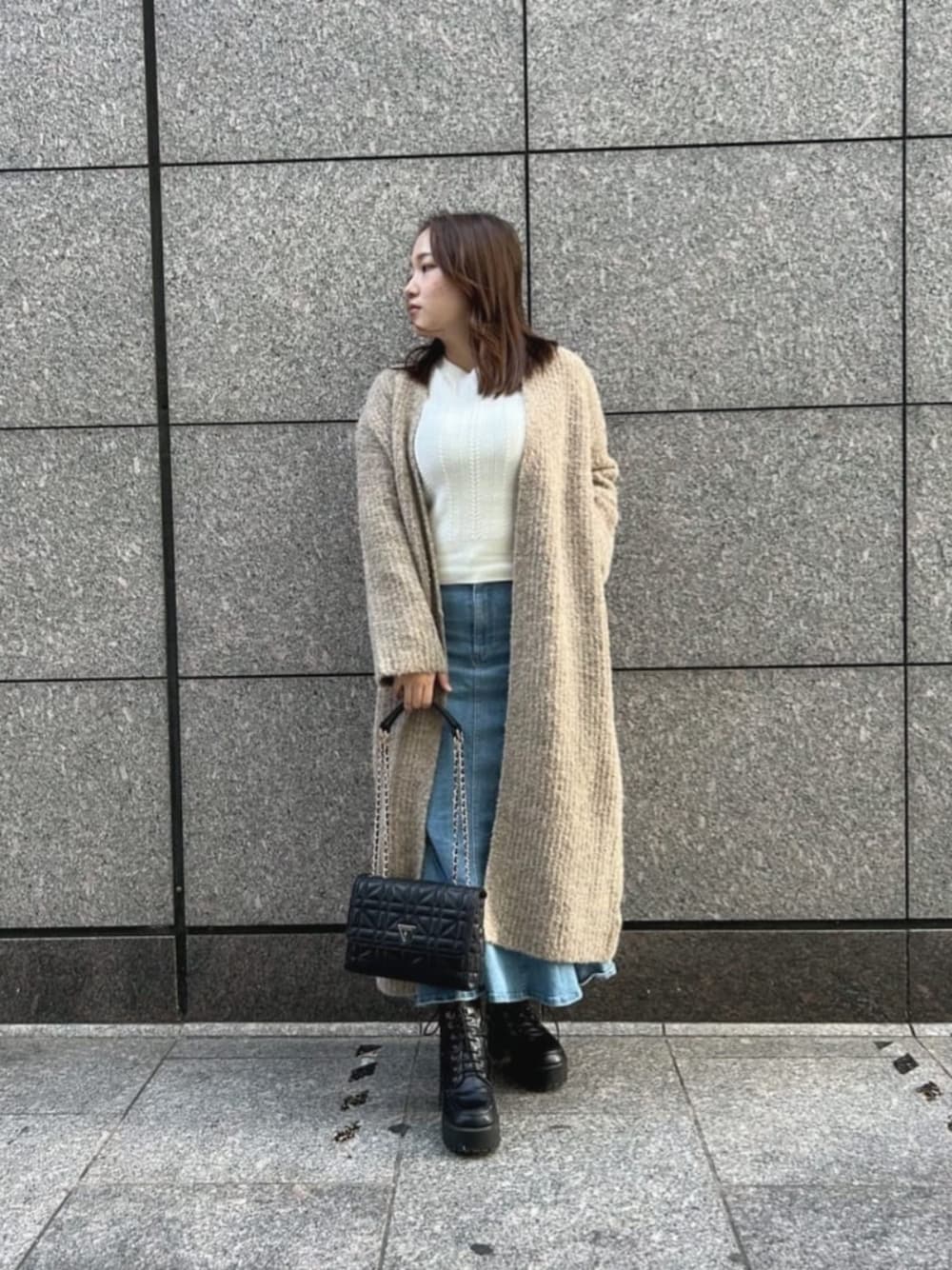 ブラック系のショルダーバッグ、ブルー系のデニムスカート、ホワイト系のニット/セーターを着用したレディースの秋コーディネートの1枚目の写真