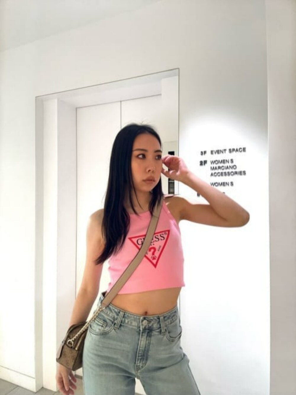 ブルー系のデニムパンツ、ピンク系のタンクトップ、ベージュ系のショルダーバッグを着用したレディースの夏コーディネートの1枚目の写真