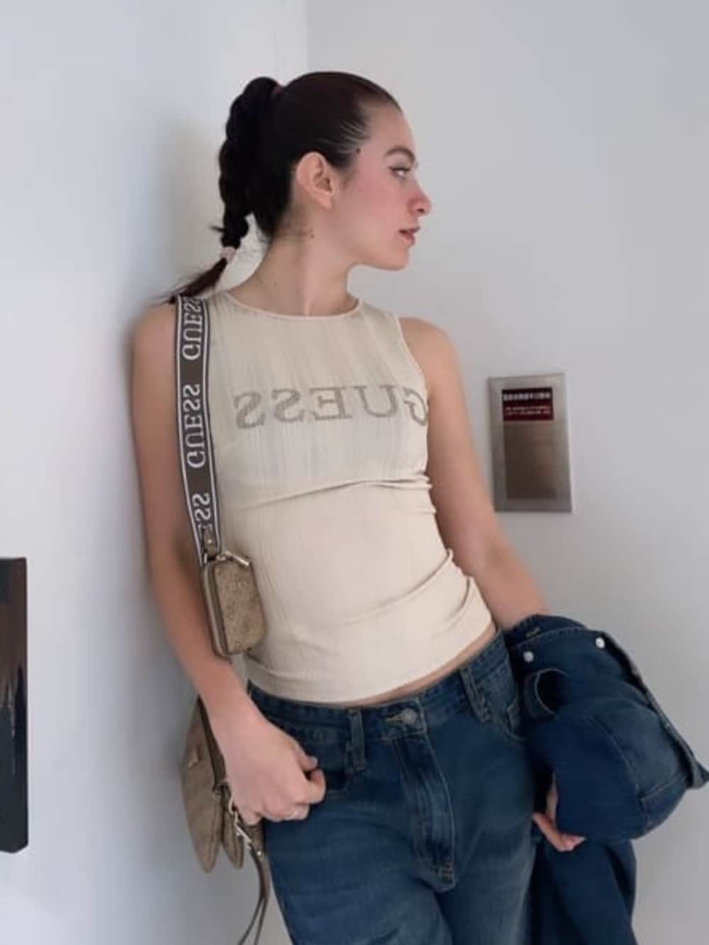 ベージュ系のショルダーバッグ、ブルー系のデニムパンツ、ベージュ系のタンクトップを着用したレディースの春コーディネートの1枚目の写真