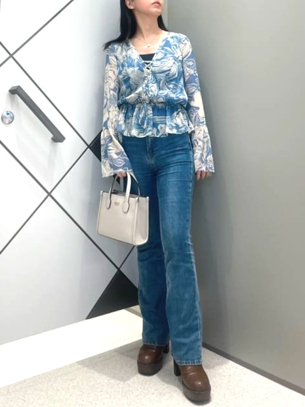 ブルー系のデニムパンツ、ブルー系のその他トップス、ベージュ系のショルダーバッグを着用したレディースの春コーディネートの1枚目の写真