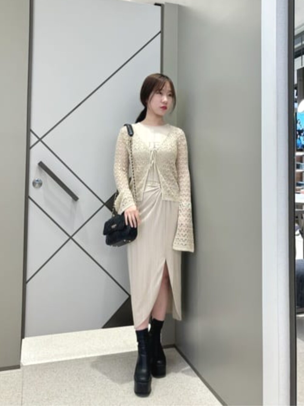 ベージュ系のタンクトップ、ブラック系のショルダーバッグ、ベージュ系のカーディガン/ボレロを着用したレディースの夏コーディネートの1枚目の写真