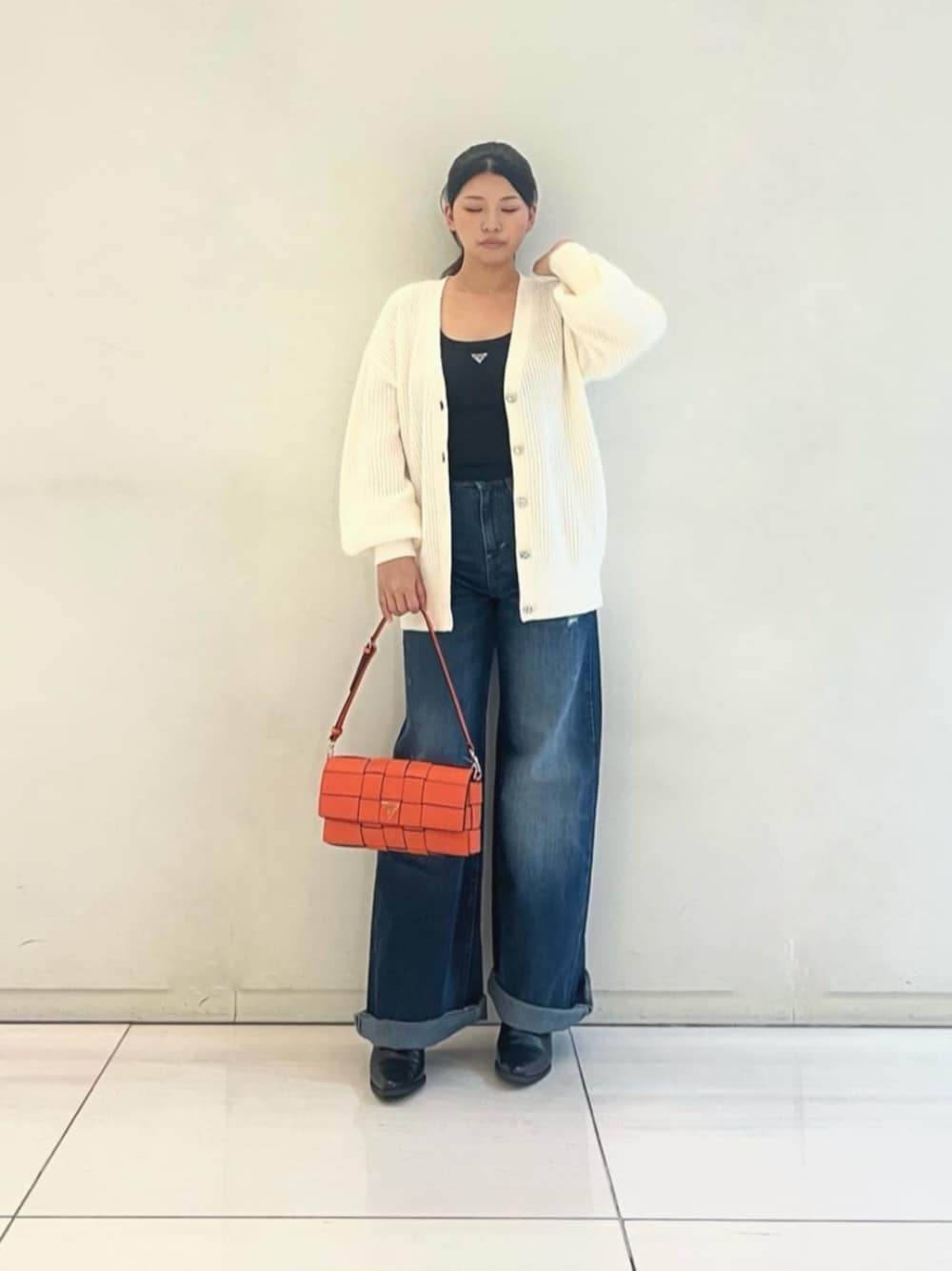 ブラック系のタンクトップ、ブルー系のデニムパンツ、オレンジ系のショルダーバッグを着用したレディースの秋コーディネートの1枚目の写真