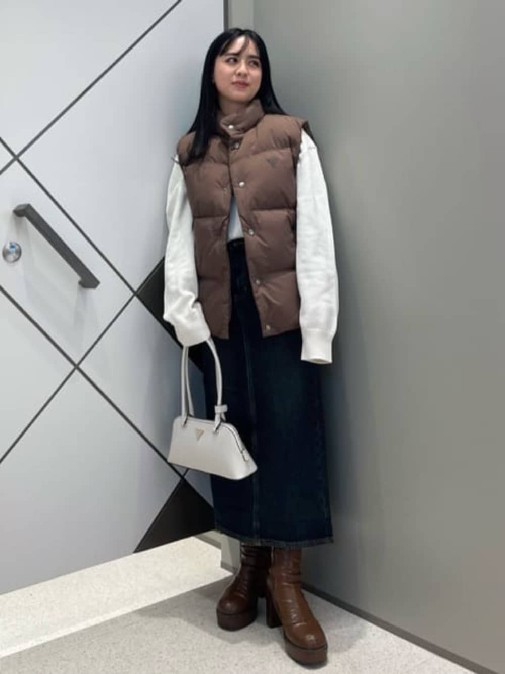 ブルー系のデニムスカート、ホワイト系のニット/セーター、ホワイト系のショルダーバッグを着用したレディースの冬コーディネートの1枚目の写真