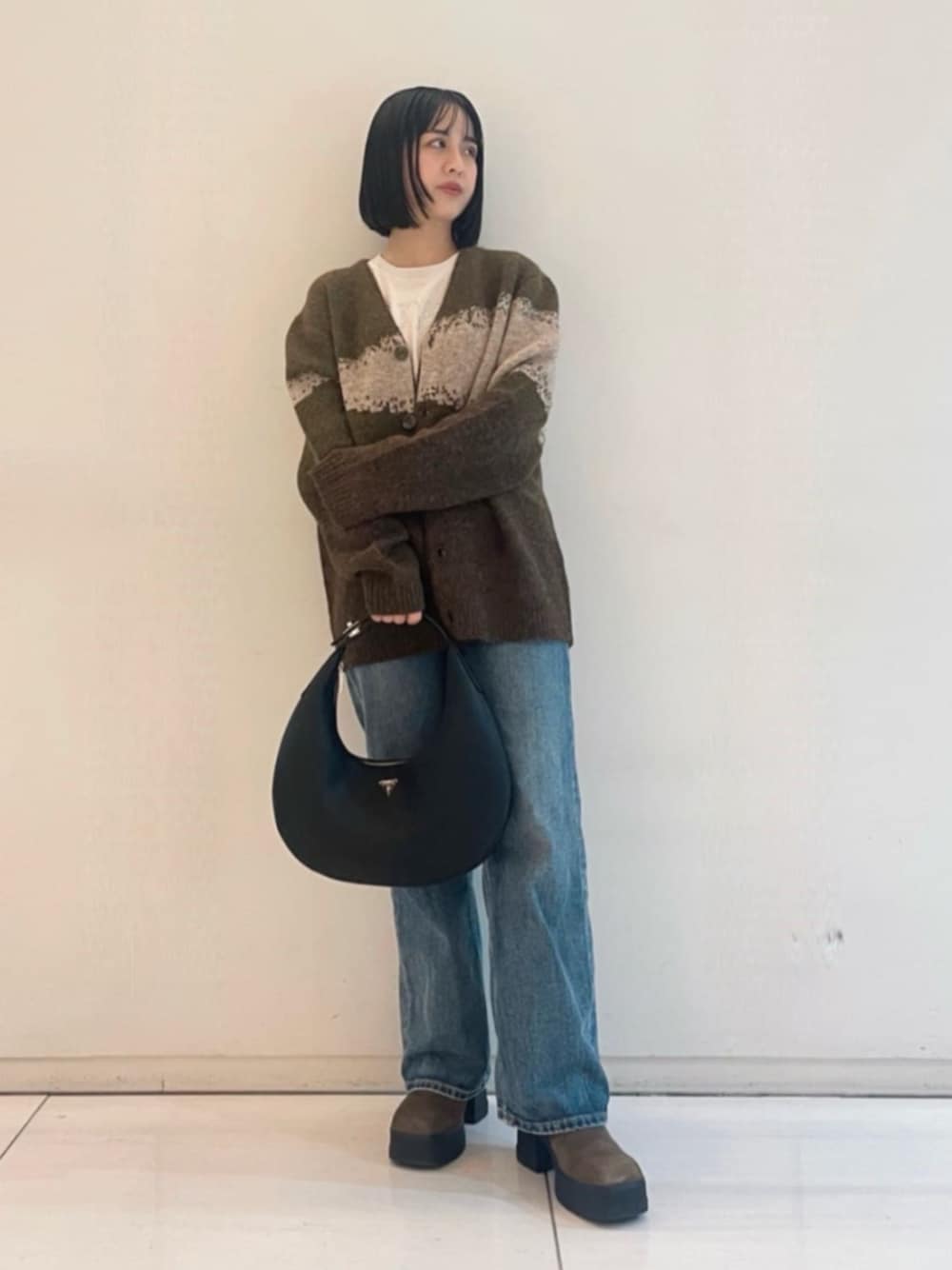 ブルー系のデニムパンツ、ブラック系のハンドバッグ、ホワイト系のTシャツ/カットソーを着用したレディースの春コーディネートの1枚目の写真