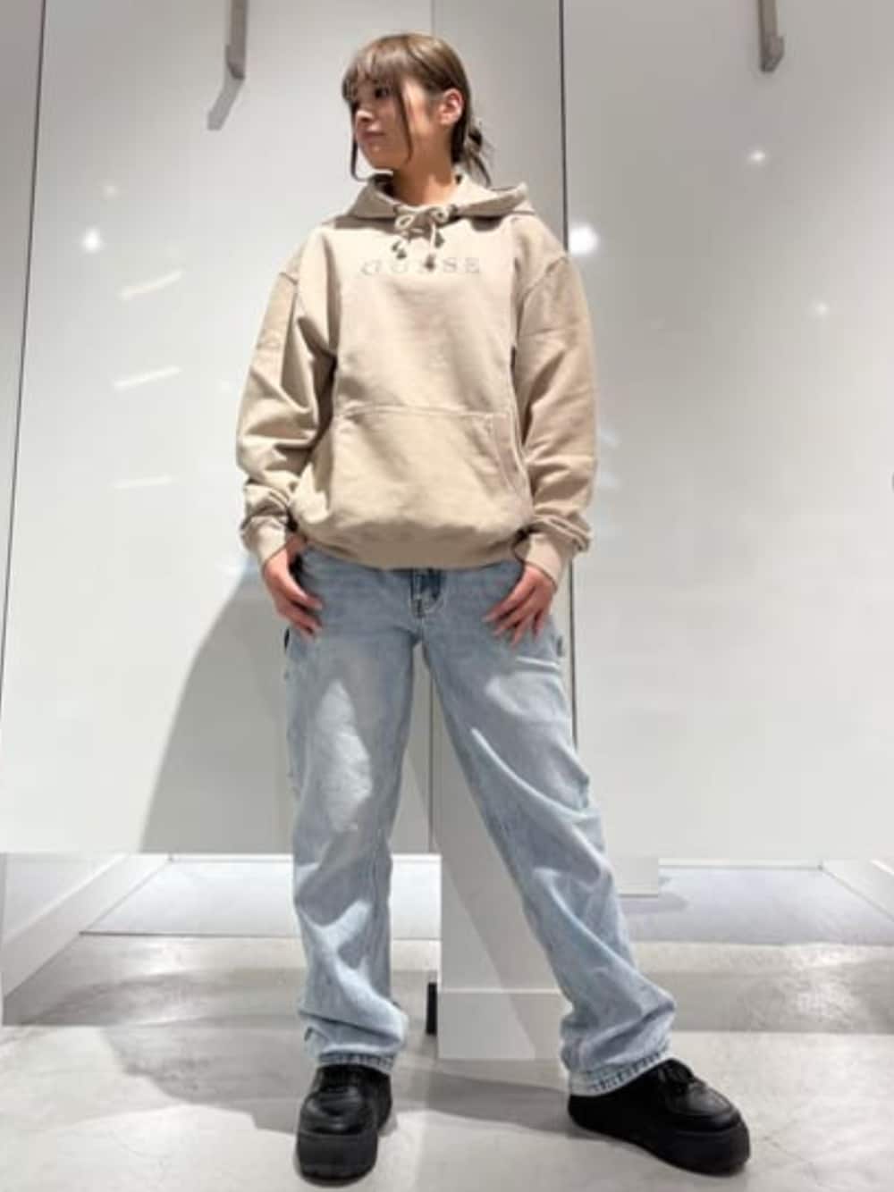 ブルー系のデニムパンツ、ベージュ系のパーカーを着用したレディースの冬コーディネートの1枚目の写真