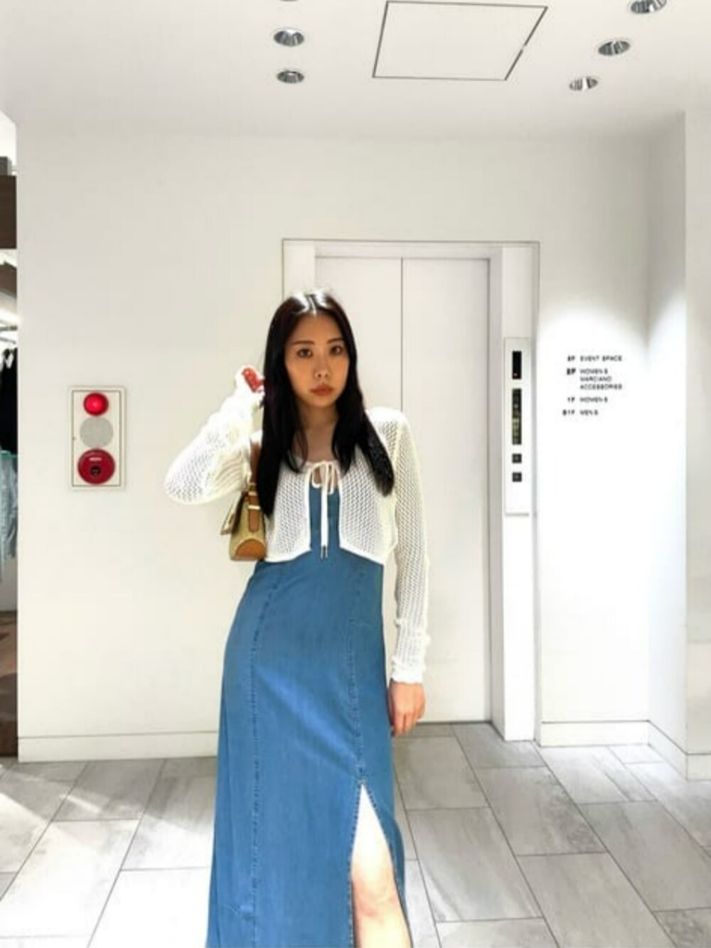 イエロー系のショルダーバッグ、ベージュ系のニット/セーター、ブルー系のワンピースを着用したレディースの夏コーディネートの1枚目の写真