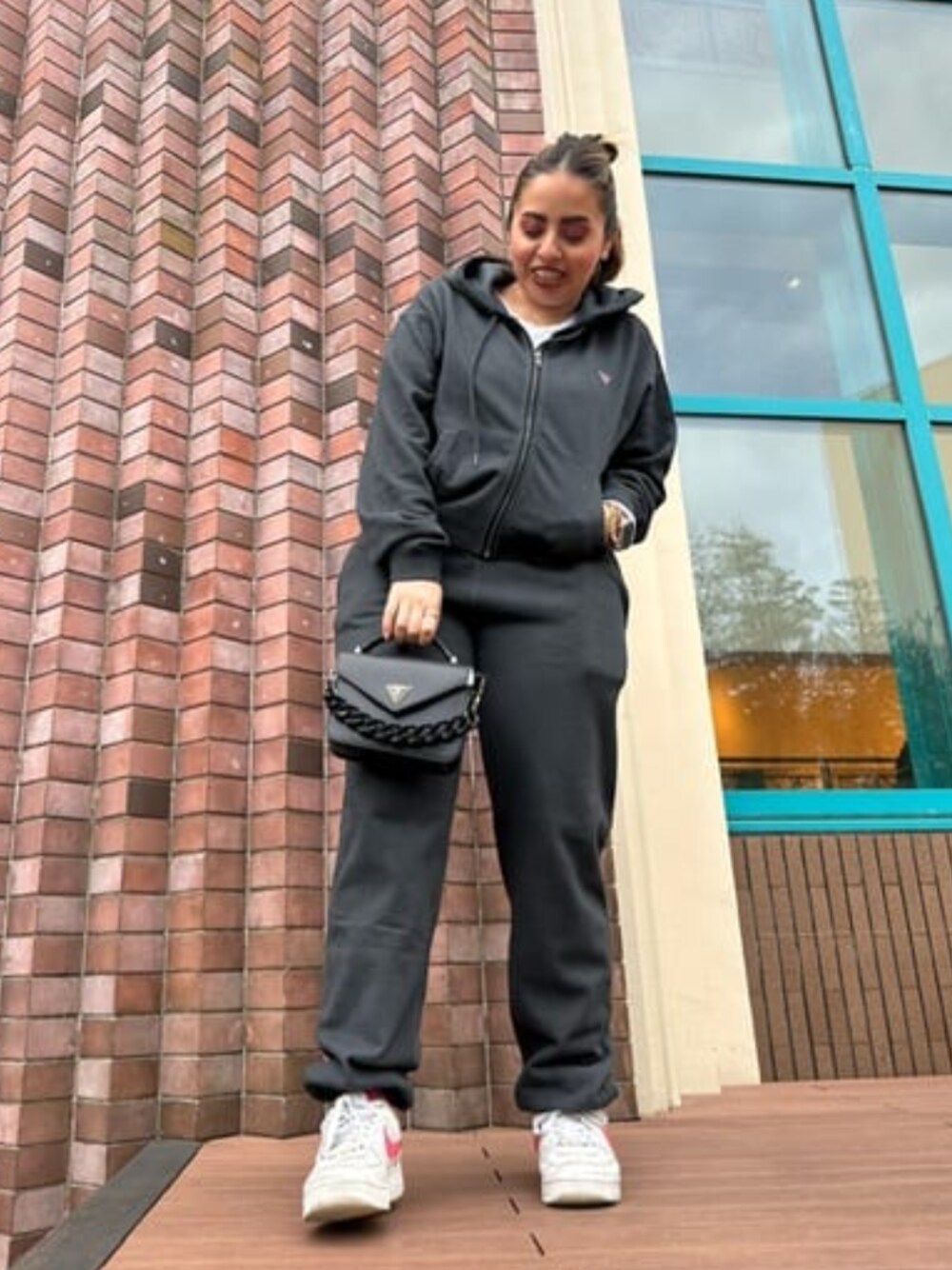 「セットアップ、スウェット、ジョガーパンツ、パーカー、オールブラックコーデ、リラックススタイル、guess」｜「GuessのCORINA Mini Top Handle Flap（ハンドバッグ、ブラック系）」を使った、GUESS JAPANさん（レディース・153cm）の春コーディネートの1枚目の写真
