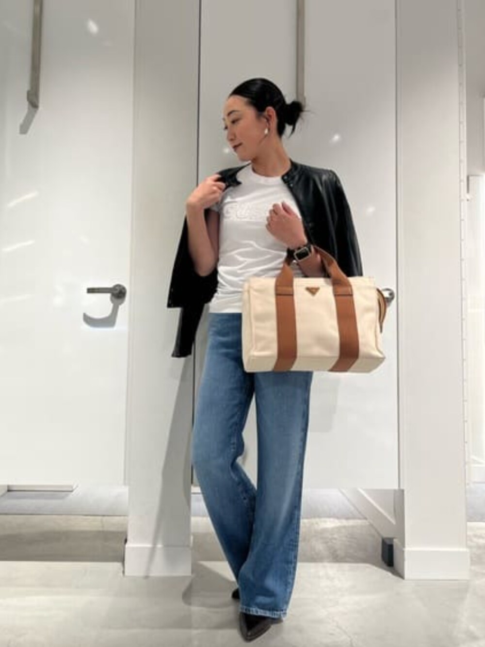 ブルー系のデニムパンツ、ブラック系のライダースジャケット、ホワイト系のTシャツ/カットソーを着用したレディースの春コーディネートの1枚目の写真