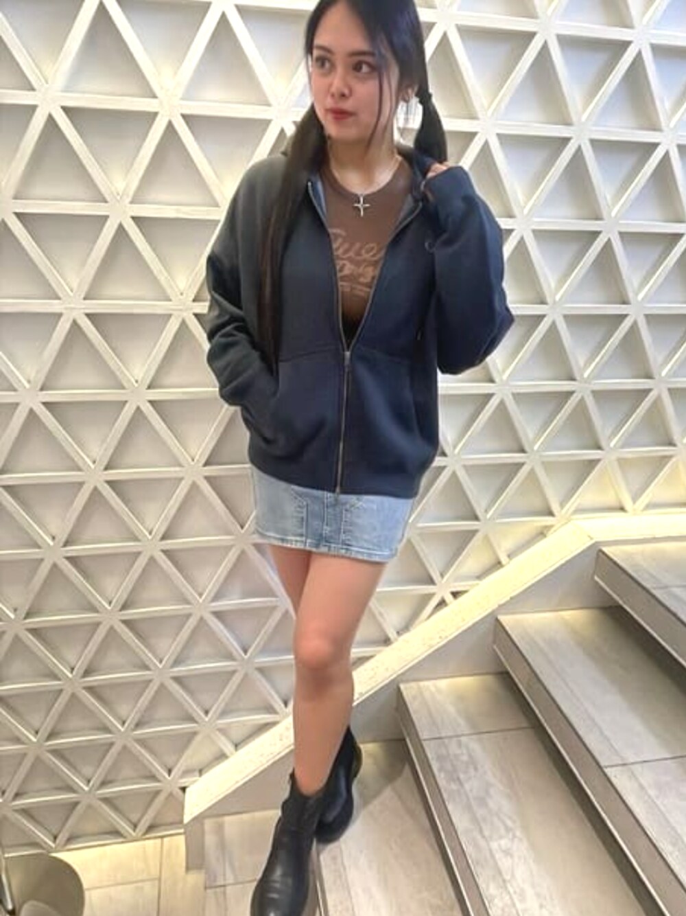 ブルー系のデニムスカート、ブラック系のパーカー、ブラウン系のTシャツ/カットソーを着用したレディースの春コーディネートの1枚目の写真