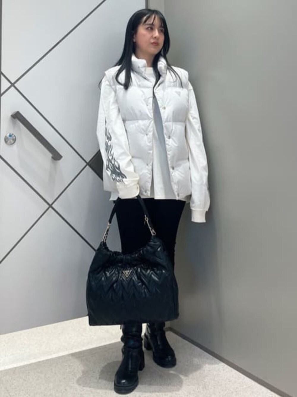 ブルー系のデニムパンツ、ホワイト系のTシャツ/カットソー、ホワイト系のダウンベストを着用したレディースの冬コーディネートの1枚目の写真