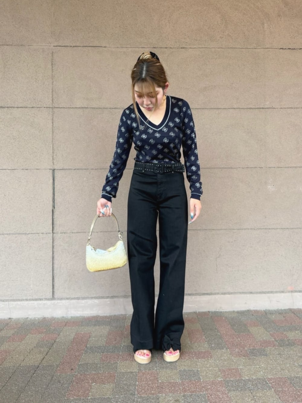 ブラック系のデニムパンツ、ブルー系のニット/セーター、ゴールド系のハンドバッグを着用したレディースの秋コーディネートの1枚目の写真