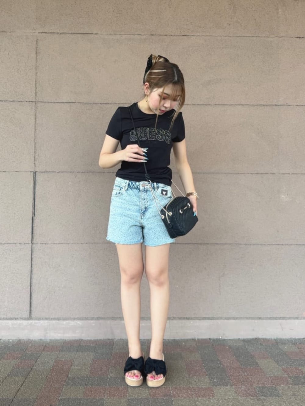 ブルー系のデニムパンツ、ブラック系のTシャツ/カットソー、ブラック系のショルダーバッグを着用したレディースの夏コーディネートの1枚目の写真