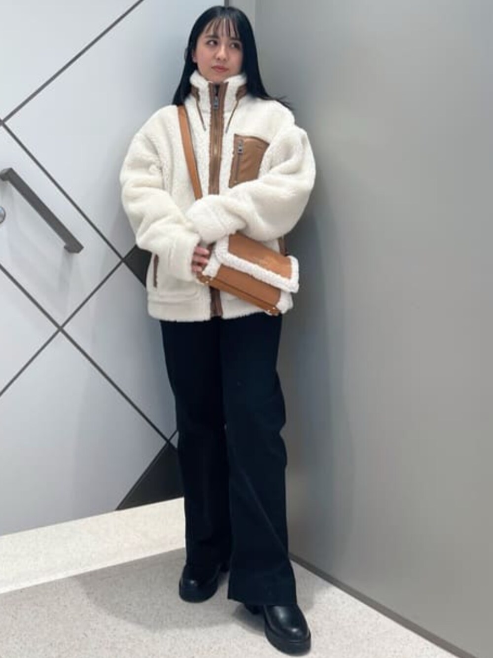 ブラウン系のショルダーバッグ、ブラック系のデニムパンツ、ホワイト系のその他アウターを着用したレディースの冬コーディネートの1枚目の写真