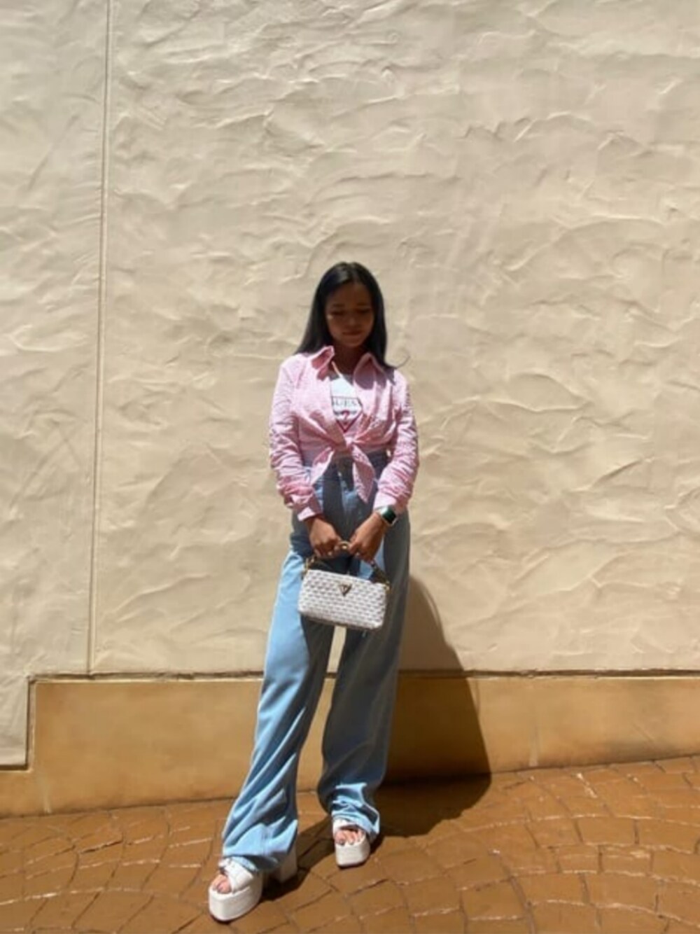 ホワイト系のタンクトップ、ホワイト系のショルダーバッグ、ブルー系のデニムパンツを着用したレディースの秋コーディネートの1枚目の写真