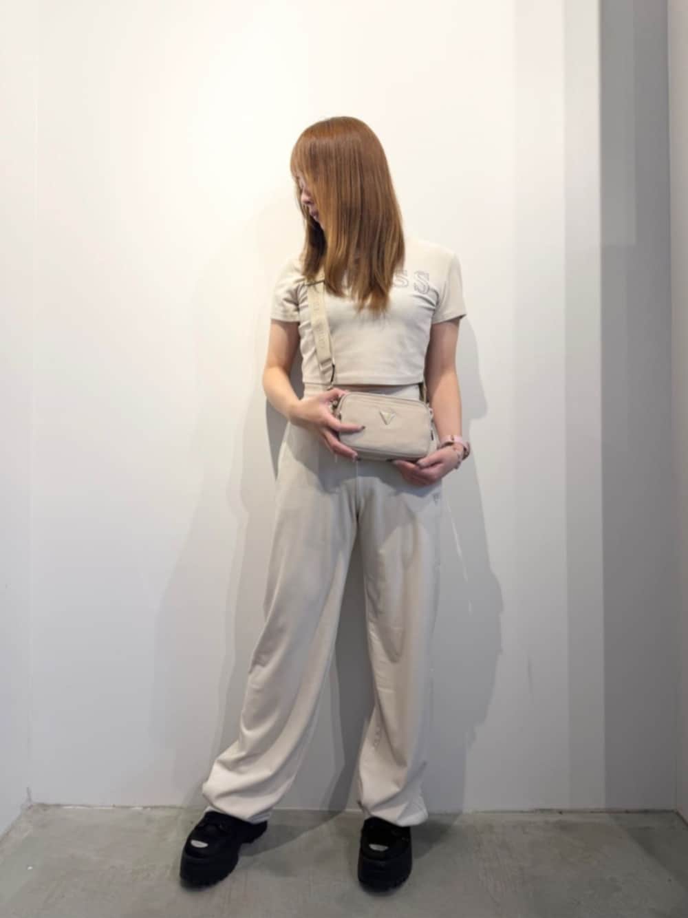 ベージュ系のショルダーバッグ、ホワイト系のTシャツ/カットソー、ホワイト系のスウェットパンツを着用したレディースの春コーディネートの1枚目の写真