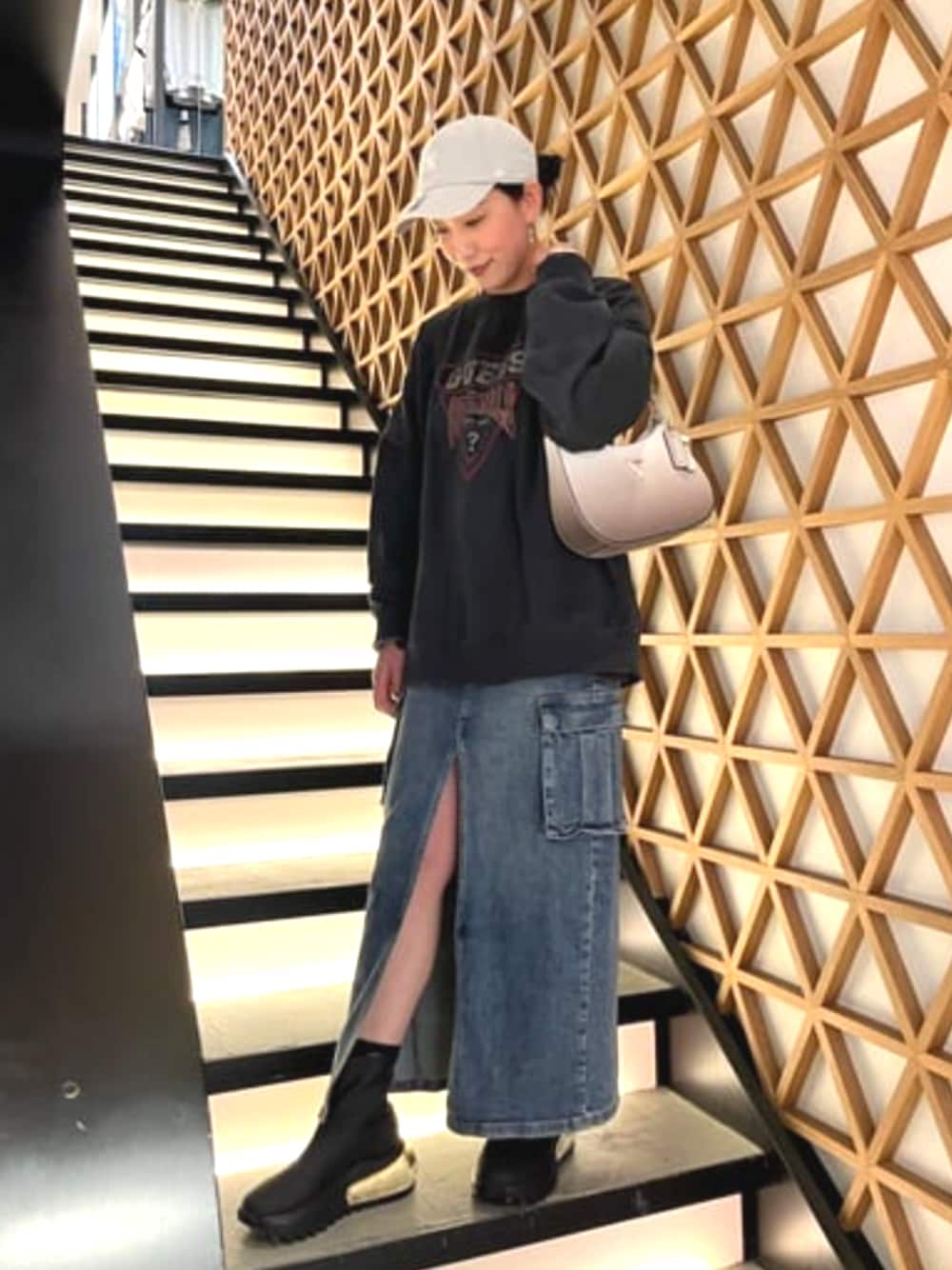 ブルー系のデニムスカート、ブラック系のスウェット、グレー系のハンドバッグを着用したレディースの春コーディネートの1枚目の写真