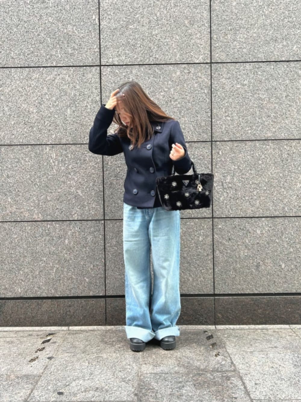 ブルー系のデニムパンツ、ブルー系のピーコート、ブラック系のショルダーバッグを着用したレディースの冬コーディネートの1枚目の写真