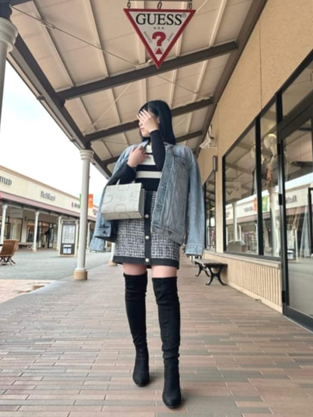 ブルー系のデニムジャケット、ブラック系のスカート、ホワイト系のトートバッグを着用したレディースの春コーディネートの1枚目の写真