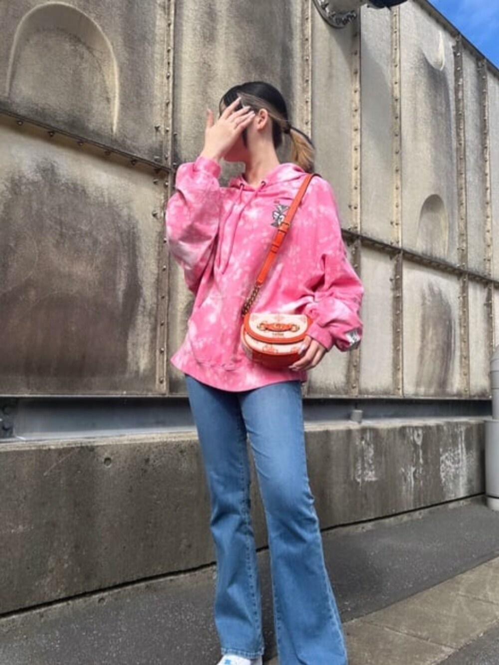 ピンク系のパーカー、オレンジ系のショルダーバッグを着用したレディースの春コーディネートの1枚目の写真