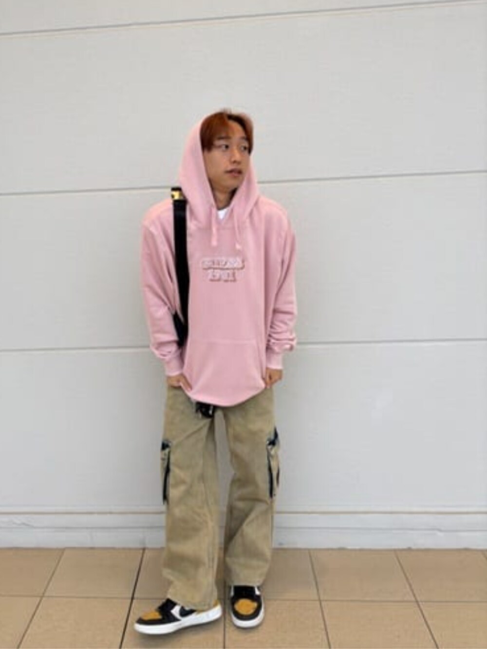 ピンク系のパーカー、イエロー系のカーゴパンツ、ブルー系のボディバッグ/ウエストポーチを着用したメンズの冬コーディネートの1枚目の写真