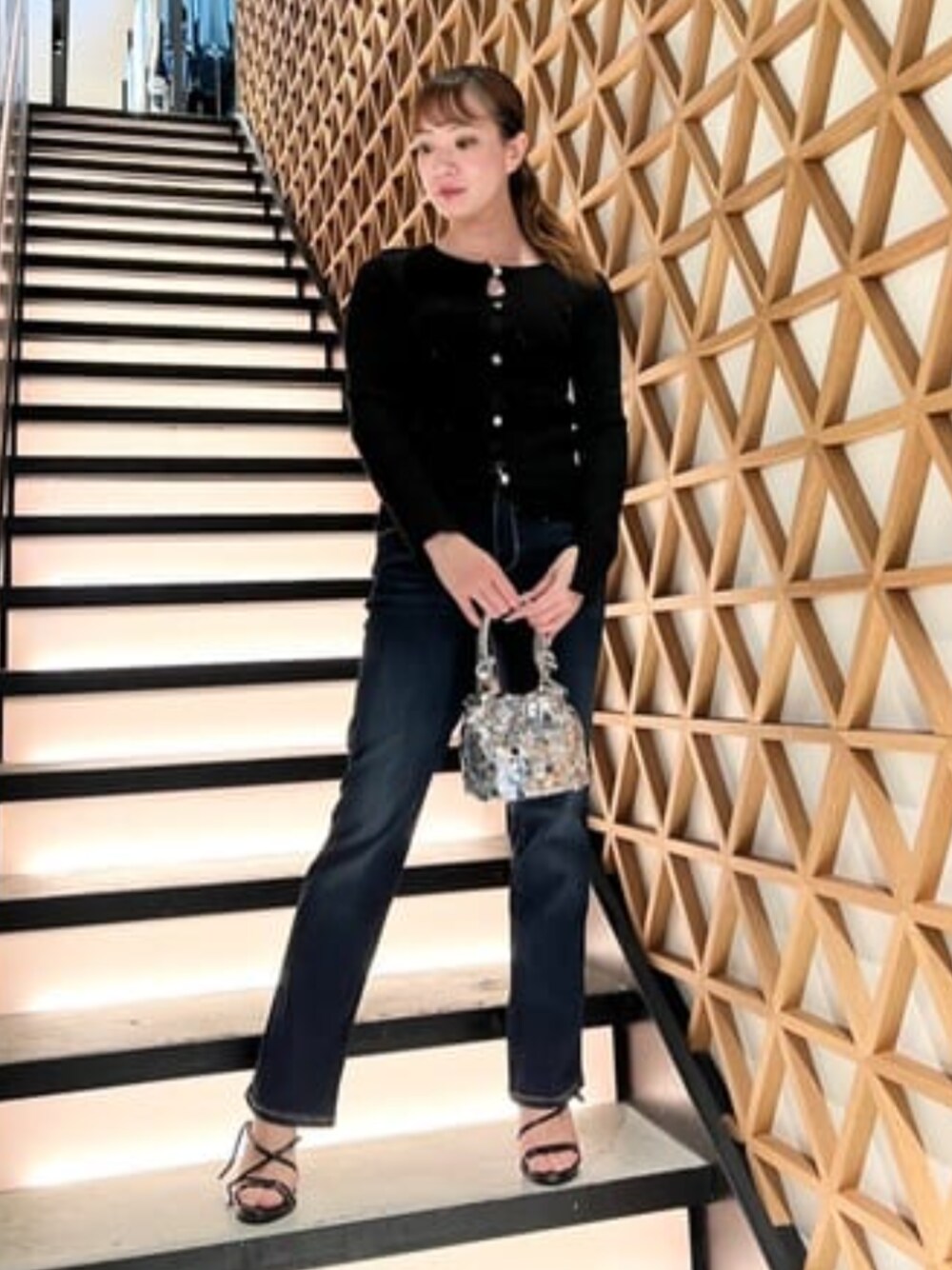 ブルー系のデニムパンツ、シルバー系のショルダーバッグ、ブラック系のニット/セーターを着用したレディースの春コーディネートの1枚目の写真