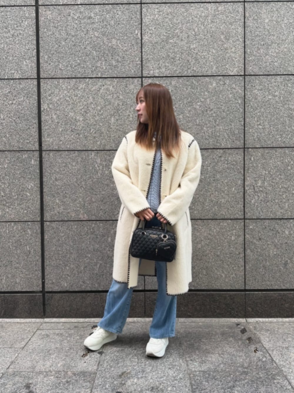 ブルー系のデニムパンツ、ブルー系のニット/セーター、ホワイト系のノーカラージャケットを着用したレディースの冬コーディネートの1枚目の写真