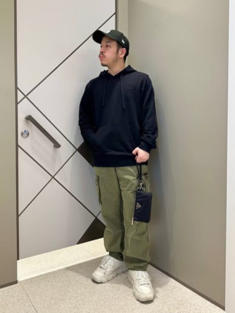 ブラック系のショルダーバッグ、ブラック系のパーカー、グリーン系のカーゴパンツを着用したメンズの夏コーディネートの1枚目の写真