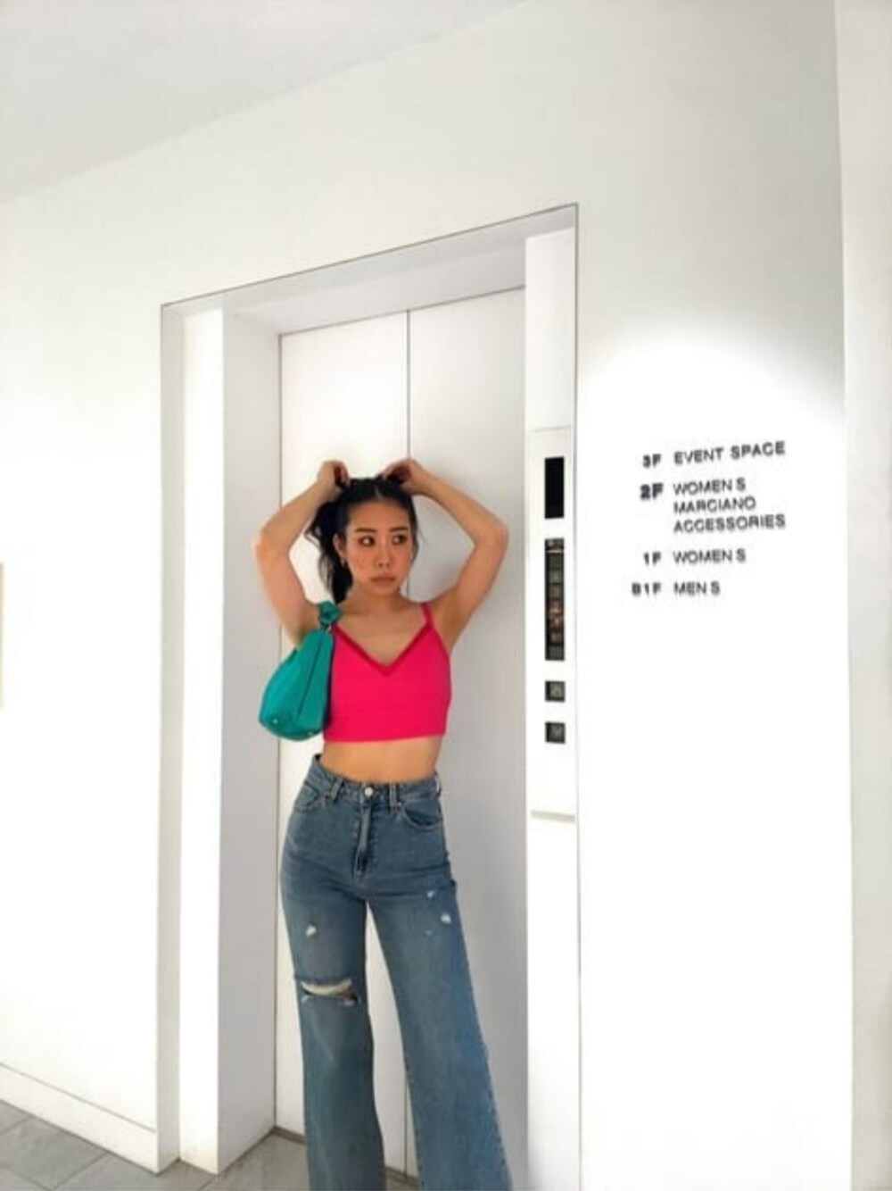 グリーン系のハンドバッグ、ブルー系のデニムパンツ、ピンク系のその他トップスを着用したレディースの夏コーディネートの1枚目の写真