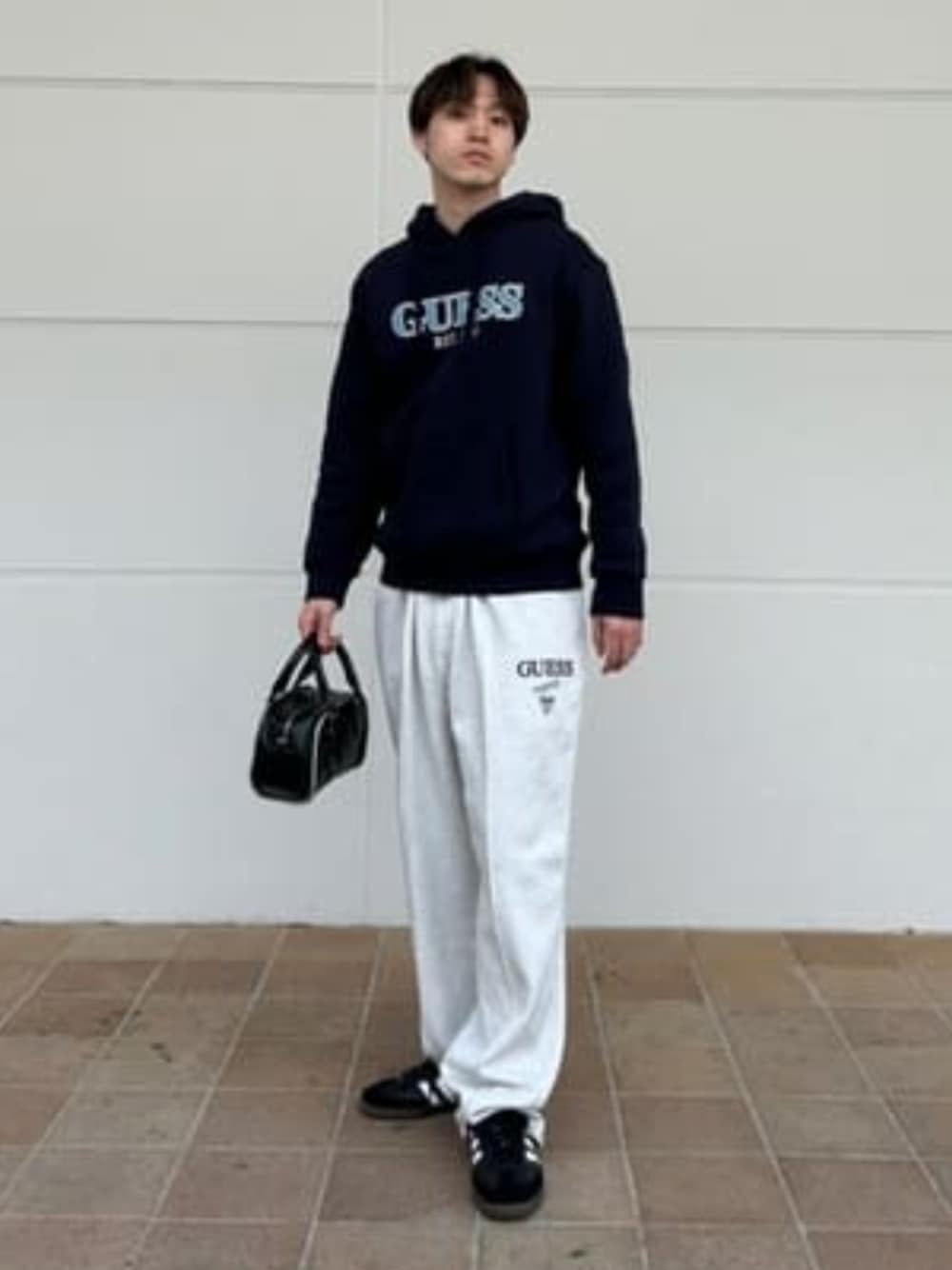 「guess、GUESS、ロゴフーディー、ロゴ、ロゴパーカー、スウェットパンツ、スウェット、スウェットコーデ、ストリートコーデ、モノトーンコーデ、モノトーン、バッグ、春コーデ、春」｜「GuessのGUESS Originals Vintage Mini Bag（ハンドバッグ、ブラック系）」を使った、GUESS JAPANさん（メンズ・178cm）の春コーディネートの1枚目の写真