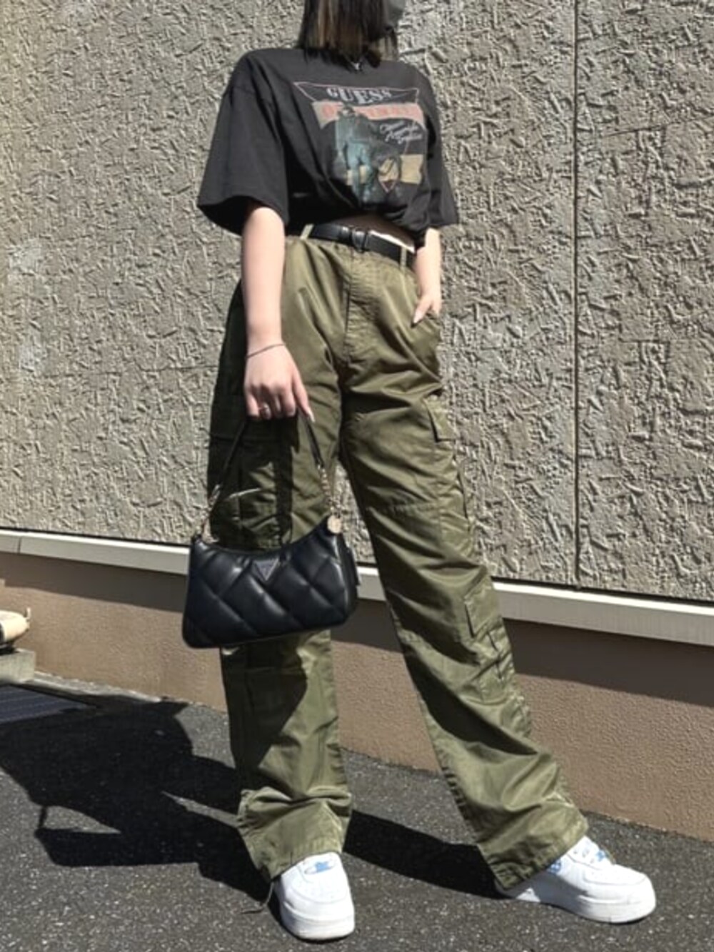 グリーン系のカーゴパンツ、ブラック系のTシャツ/カットソー、ブラック系のハンドバッグを着用したレディースの春コーディネートの1枚目の写真