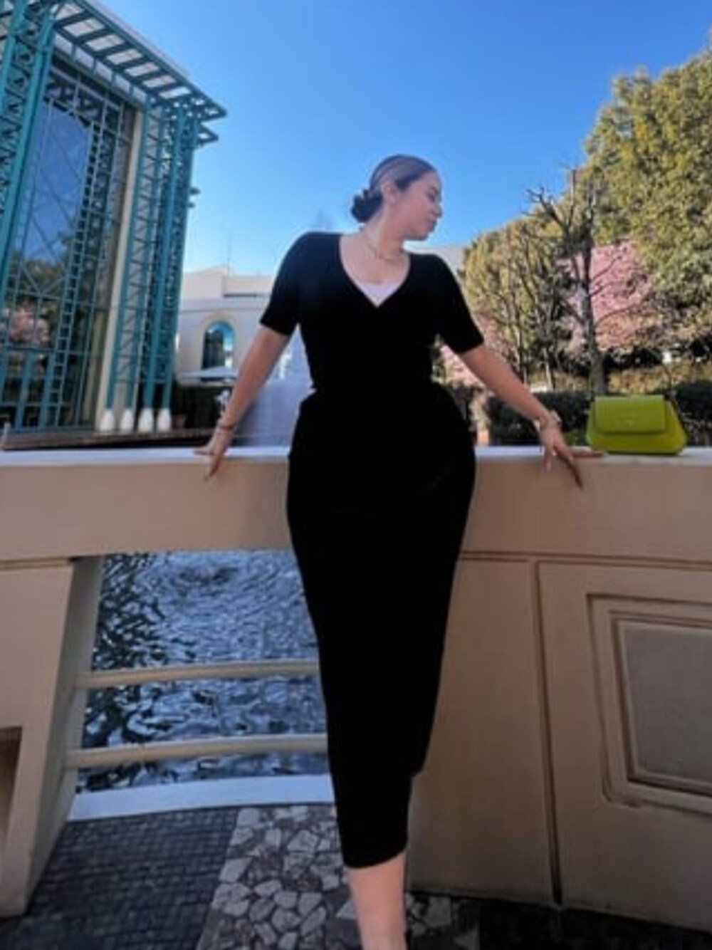 グリーン系のショルダーバッグ、ブラック系のその他トップス、ゴールド系のブレスレットを着用したレディースの春コーディネートの1枚目の写真