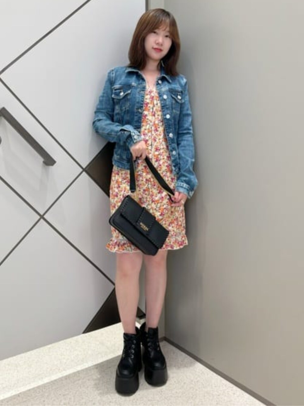 ブルー系のデニムジャケット、オレンジ系のワンピースを着用したレディースの冬コーディネートの1枚目の写真