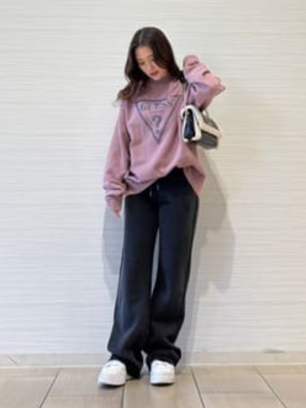 ブラック系のスウェットパンツ、ピンク系のスウェット、ブラック系のショルダーバッグを着用したレディースの冬コーディネートの1枚目の写真