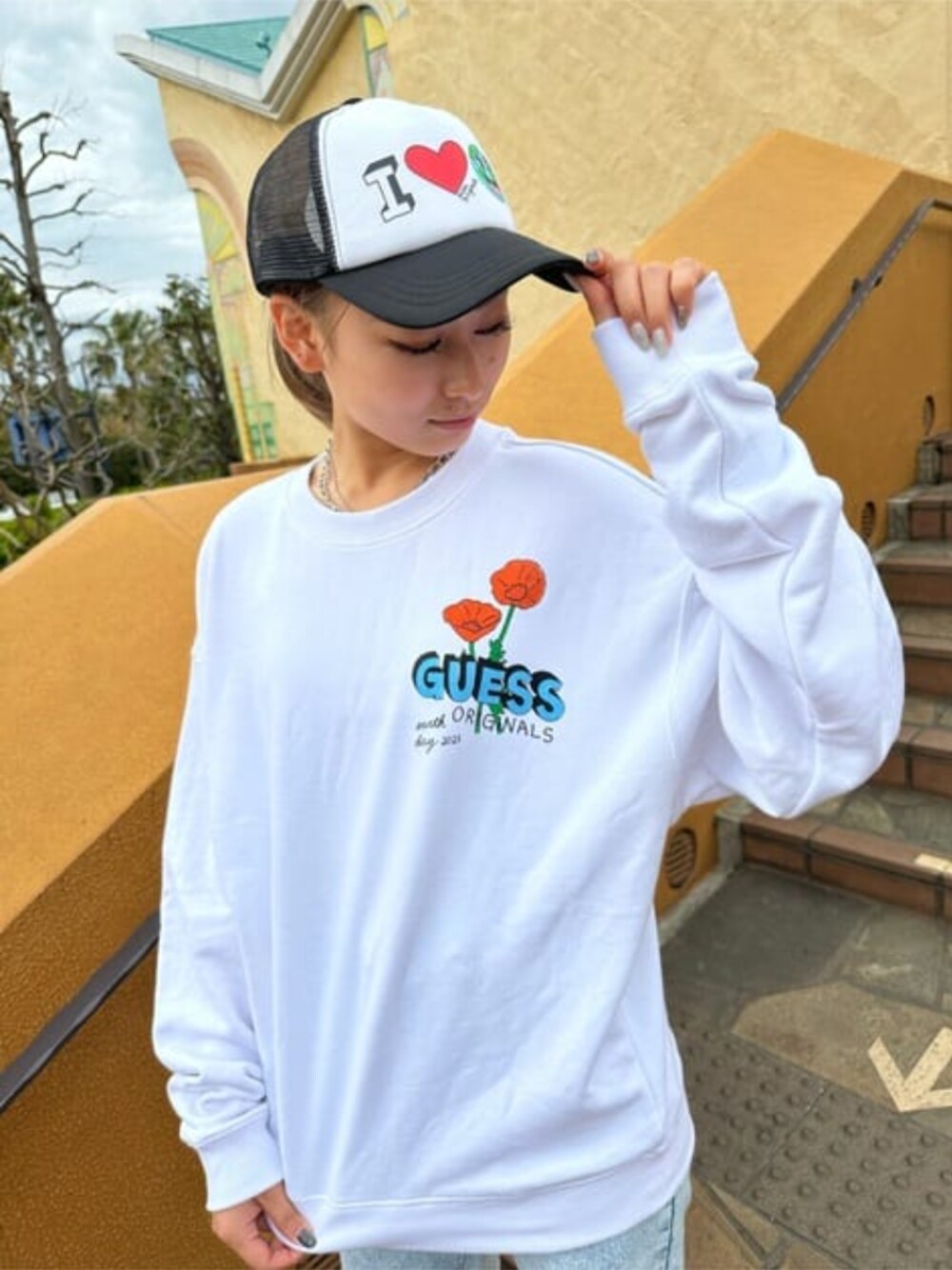 ホワイト系のスウェット、ブルー系のデニムパンツ、ブラック系のハットを着用したレディースの春コーディネートの1枚目の写真